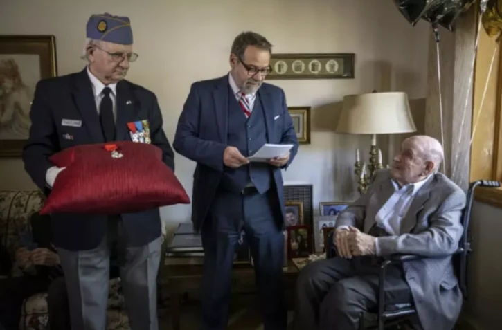 Le consul général de France Damien Laban (c) remet la Légion d'honneur à Jack Hausman (d), vétéran de la Seconde Guerre mondiale, lors d'une cérémonie, le 26 avril 2024 à New York ( AFP / ANGELA WEISS )