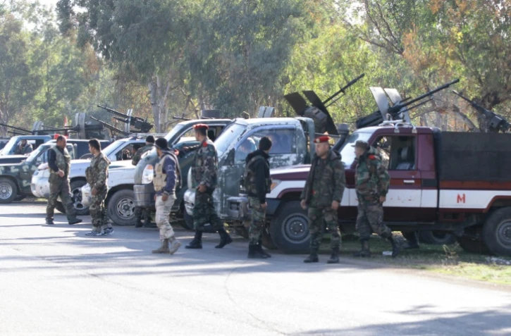 Des membres des forces gouvernementales syriennes montent la garde alors que des rebelles évacuent un quartier de Homs le 9 décembre 2015