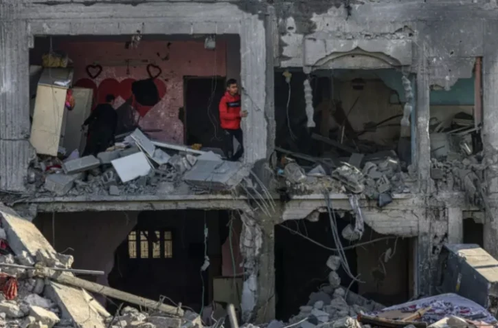 Des Palestiniens dans les décombres d'un bâtiment où deux otages auraient été détenus avant d'être secourus lors d'une opération des forces de sécurité israéliennes à Rafah, le 12 février 2024 dans le sud de la bande de Gaza ( AFP / SAID KHATIB )