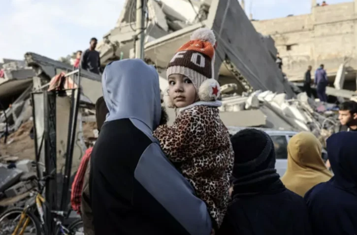 Un Palestinien porte un enfant devant les décombres d'une maison détruite par un bombardement israélien à Rafah, dans le sud de la bande de Gaza, le 3 février 2024 ( AFP / SAID KHATIB )
