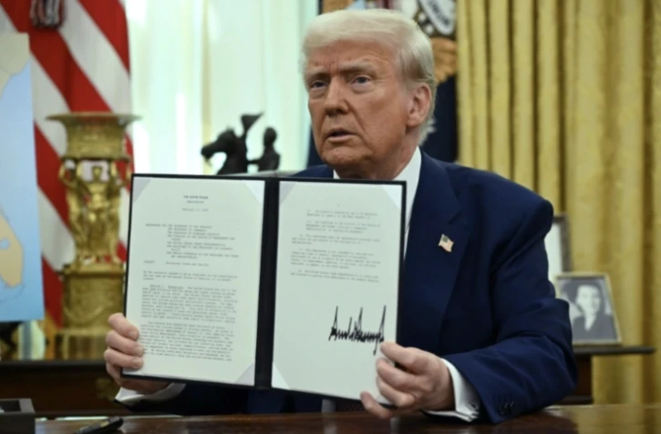 Le président américain Donald Trump montre le décret qu'il vient de signer sur les "droits de douane réciproques" dans le Bureau ovale de la Maison Blanche, le 13 février 2025 à Washington ( AFP / ANDREW CABALLERO-REYNOLDS )