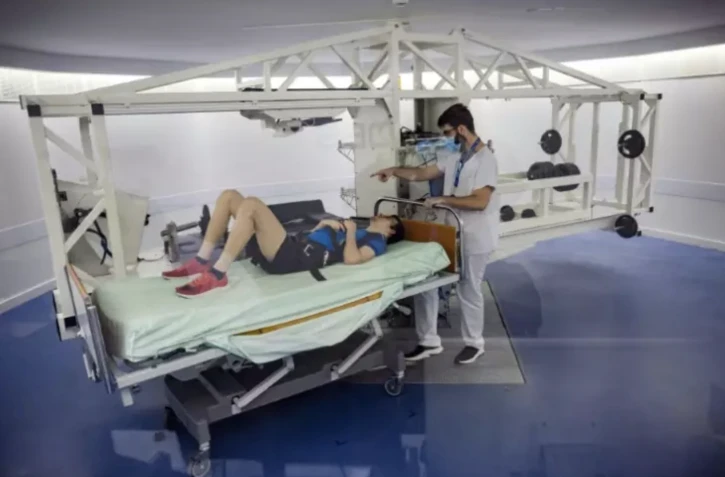 Un volontaire allongé sur une centrifugeuse est examiné par un médecin lors d'une expérience à la clinique de Medes, filiale santé du Centre national d'études spatiales (CNES), à Toulouse, le 23 mai 2023 ( AFP / Lionel BONAVENTURE )