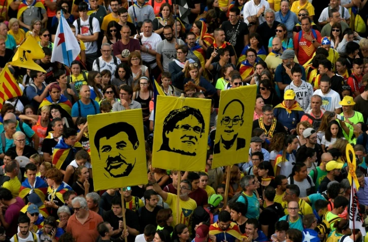 Des personnes tiennent des portraits des séparatistes catalans Jordi Sanchez, Carles Puigdemont et Jordi Turull lors d'une manifestation à Barcelone, le 18 octobre 2019