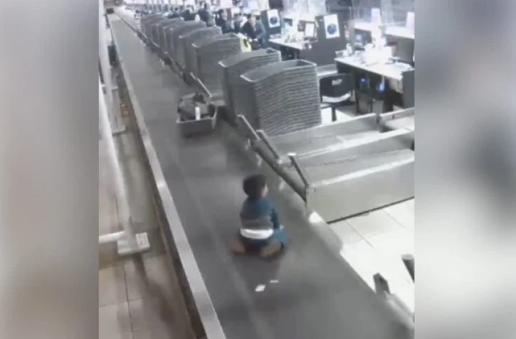 Un enfant sur le tapis à bagage