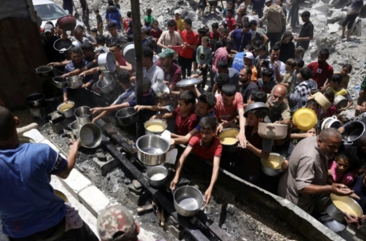 Des déplacés palestiniens se rassemblent pour collecter des repas gratuits auprès d'une association caritative à Jabalia, dans le nord de la bande de Gaza, le 19 mai 2025 ( AFP / Bashar TALEB )