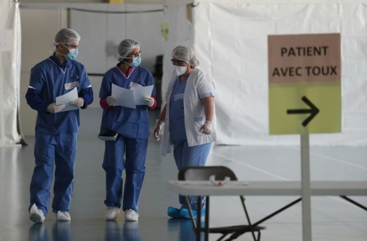 Des membres du personnel médical en combinaison de protection organisent l'accueil des patients au "centre d'urgences Covid-19" aménagé dans un gymnase, le 23 mars 2020 à Taverny, dans le Val d'Oise