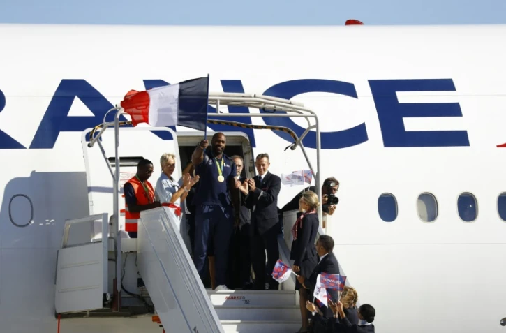 Le double médaillé d'or olympique en judo Teddy Riner, drapeau à la main, à sa descente de l'avion de retour des Jeux de Rio sur le tarmac de l'aéroport Charles de Gaulle à Roissy le 23 août 2016