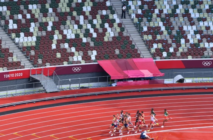 Des athlètes passent devant des tribunes vides, en raison du huis clos imposé par la pandémie, lors des séries du 1500 m aux Jeux Olympiques de Tokyo 2020, le 3 août 2021 au Stade Olympique