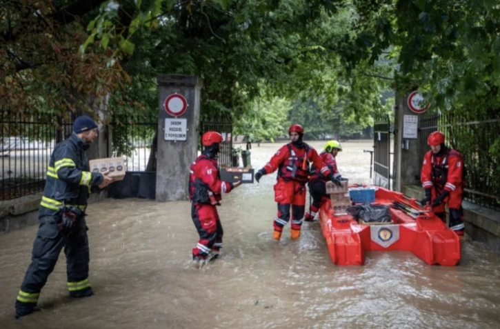 Des pompiers chargent une embarcation de nourriture pour des personnes âgées dans une maison de retraite dans la ville inondée de Stupava, en Slovaquie, le 15 septembre 2024 ( AFP / TOMAS BENEDIKOVIC )