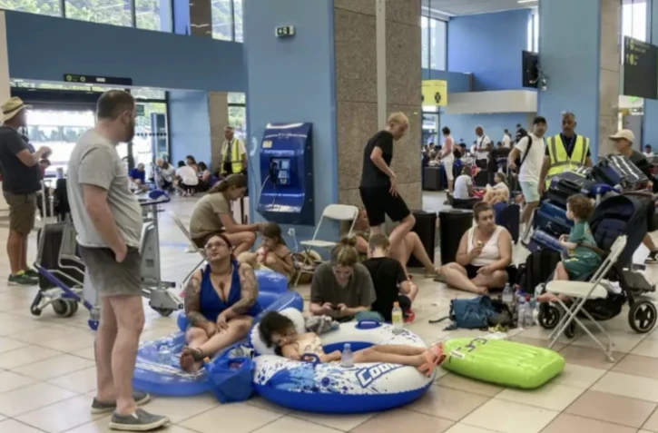 Des touristes attendent leur évacuation dans le hall des départs de l'aéroport international de Rhodes, en Grèce, le 23 juillet 2023 ( AFP / Will VASSILOPOULOS )