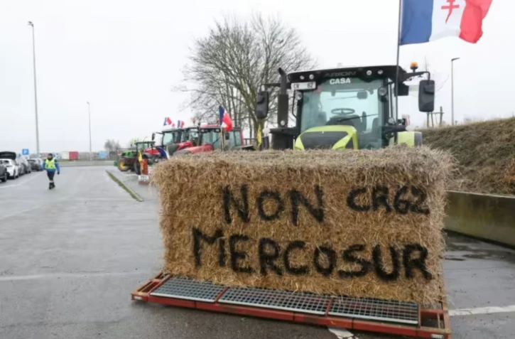 Une botte de foin "Non au Mercosur" sur un tracteur alors que des agriculteurs participent à un blocage sur l'autoroute A1 près de Fresnes-lès-Montauban, le 12 janvier 2026 dans le Pas-de-Calais ( AFP / Francois LO PRESTI )