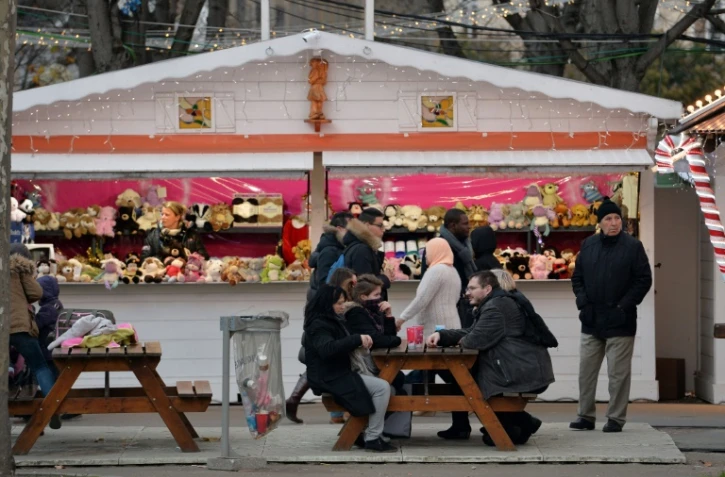 Des personnes s'asseoient devant un stand de jouets, au marché de Noël à Paris, le 24 décembre 2015 