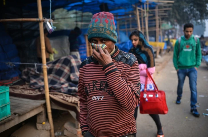 Un passant tente  de se protéger de la pollution le 18 décembre 2015 dans le quartier d'Anand Vihar à New Delhi