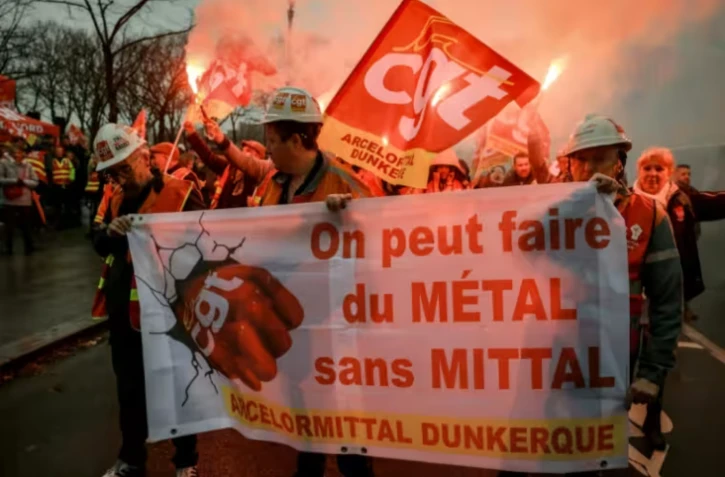 Des employés d'ArcelorMittal, venus en bus de leurs sites du Nord et de la Moselle, défilent lors d'une action organisée par la CGT sur l'Esplanade des Invalides, en soutien au projet de loi LFI, examiné par les députés, le 27 novembre 2025 à Paris ( AFP / Alain JOCARD )