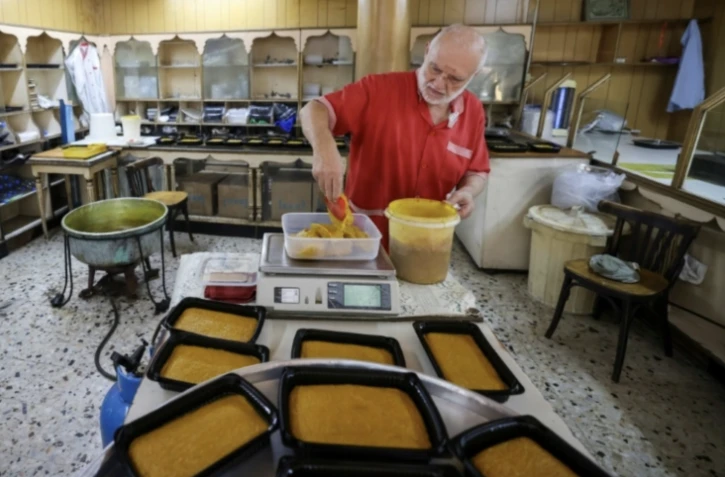 Hassan al-Makari pèse la mfatka dans son échoppe à Beyrouth, le 29 août 2024 au Liban ( AFP / ANWAR AMRO )