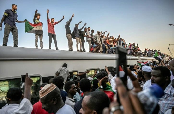Des manifestants venus de la ville d'Atbara (centre du Soudan) font le signe de la victoire en arrivant en train à Khartoum le 23 avril 2019
