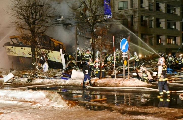 Des pompiers viennent en aide à des blessés après l'explosion d'un restaurant à Sapporo, sur l'île septentrionale japonaise de Hokkaido, le 16 décembre 2018