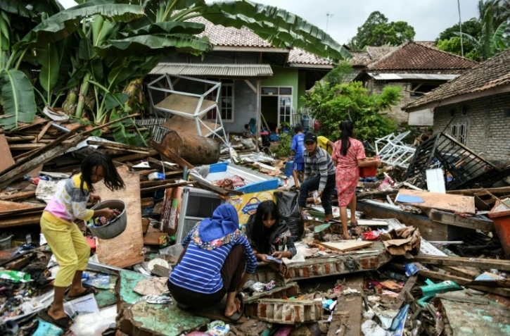 Des habitants récupèrent des affaires personnels dans les décombres de leurs maisons, le 25 décembre 2018 à Rajabasa, trois jours après le tsunami qui a frappé l'Indonésie
