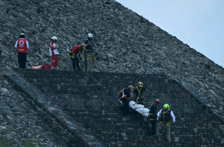 Des experts médico-légaux et des membres de la Croix-Rouge transportent un corps sur la pyramide de la Lune, sur le site archéologique de Teotihuacan, après une fusillade survenue à Teotihuacan, dans l'Etat de Mexico, le 20 avril 2026