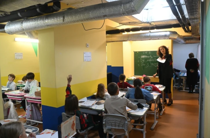 Des écoliers ont classe dans un abri installé au sous-sol de leur école primaire pendant une alerte aérienne en banlieue de Kiev, le 20 octobre 2026