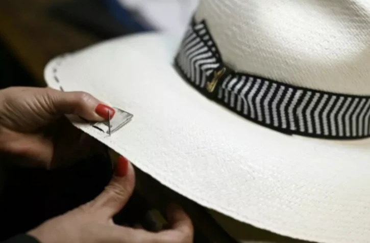 Une artisane coud le rebord d'un chapeau Borsalino, dans sa manufacture à Alexandrie dans le nord de l'Italie, le 28 mars 2023 ( AFP / GABRIEL BOUYS )