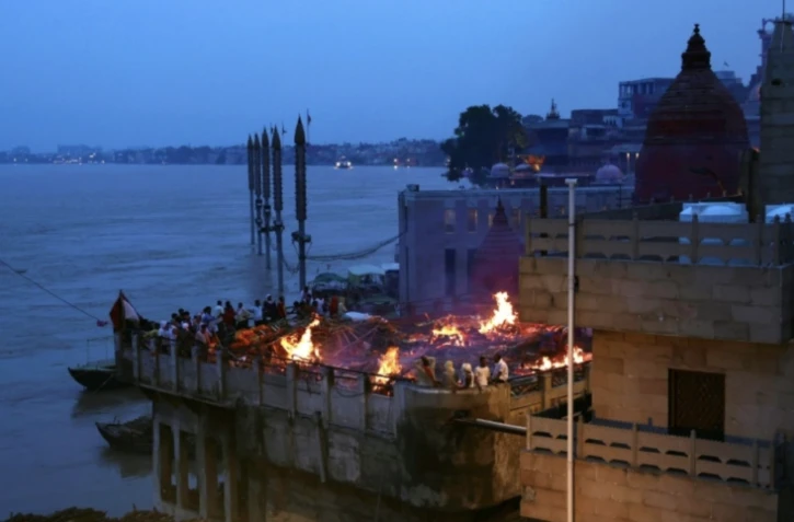 Des fidèles hindous se tiennent près des bûchers funéraires à Varanasi, le long des rives du Gange en Inde, le 31 août 2024 ( AFP / Niharika KULKARNI )