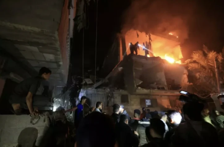 Des personnes utilisent les lampes de leurs téléphones mobiles pour chercher des victimes dans les décombres d'un immeuble touché par une frappe israélienne, le 6 décembre 2023 à Rafah, dans la bande de Gaza ( AFP / MAHMUD HAMS )