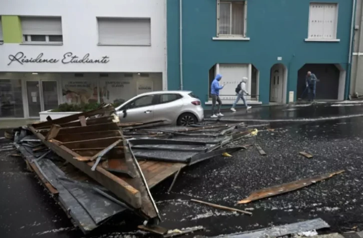 Des piétons passent près du toit arraché d'un immeuble résidentiel tombé dans une rue de Brest, après le passage de la tempête Ciaran, le 2 novembre 2023 dans le Finistère ( AFP / DAMIEN MEYER )