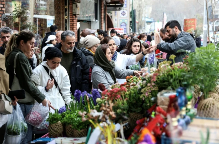 Des Iraniens achètent des fleurs au bazar Tajrish, dans le nord de Téhéran, le 19 mars 2026, à la veille de Norouz, le Nouvel An persan