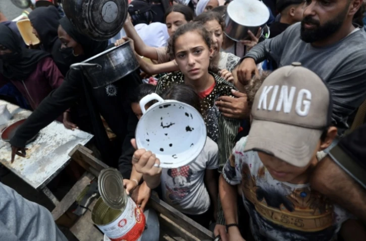 Des enfants se pressent à une distribution de repas chauds à Nousseirat, dans le centre de la bande de Gaza, le 4 juin 2025 ( AFP / Eyad BABA )
