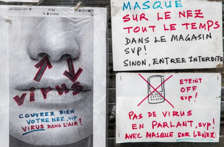 Affichettes sur la devanture d'un commerce à Paris demandant le port du masque, le 27 juin 2021