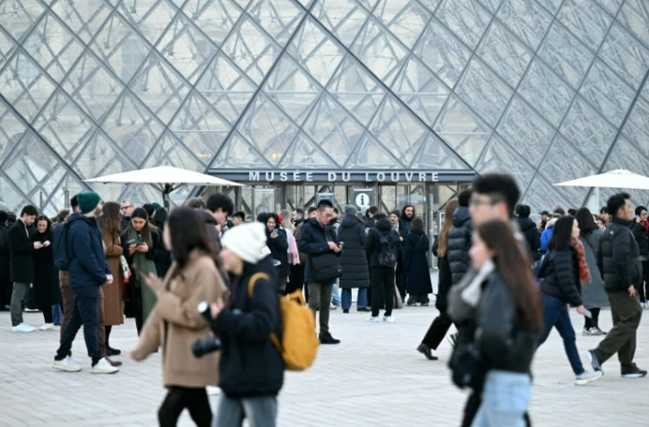 Des visiteurs devant la pyramide du Louvre le 15 décembre 2025 à Paris