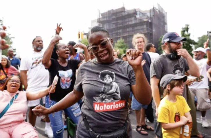 Une femme danse au milieu d'une foule lors d'un concert du DJ américain Mister Cee organisé à l'occasion des 50 ans du hip-hop à Brooklyn, à New York, le 5 août 2023 ( AFP / KENA BETANCUR )