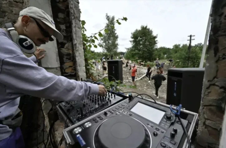 Un DJ joue de la musique électro pour les bénévoles de "Réparer ensemble", dans le village de Iaguidné, dans le nord de l'Ukraine, le 8 juillet 2023 ( AFP / Genya SAVILOV )