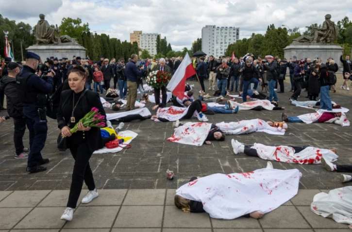 Des manifestants allongés sur le sol, simulent des corps de victimes, pour protester contre l'invasion russe de l'Ukraine, au mausolée des soldats soviétiques à Varsovie, en Pologne, le 9 mai 2025
