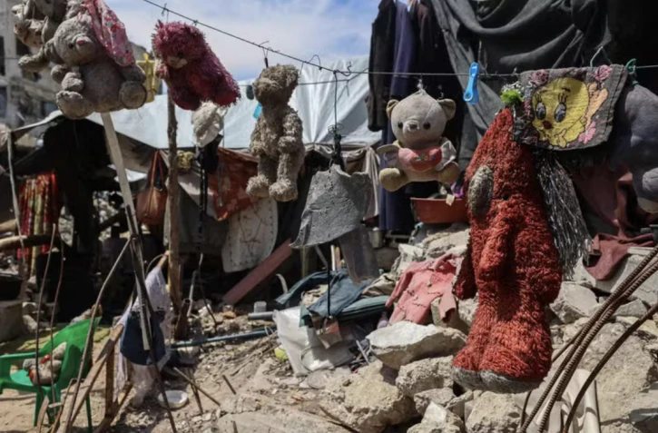 Des jouets ayant appartenu aux enfants du Palestinien Wissam Wishah – Saïd, Salma et Eline –, tués lors de bombardements israéliens, sont suspendus à une corde à linge sur les décombres de leur maison, dans le camp de réfugiés d’Al-Bureij, dans le centre de la bande de Gaza, le 1ᵉʳ mai 2025. EYAD BABA / AFP 