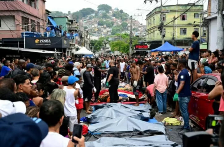Des habitants se tiennent devant des corps alignés dans une des favelas du Complexo da Penha, à Rio de Janeiro, le 29 octobre 2025 ( AFP / Pablo PORCIUNCULA )