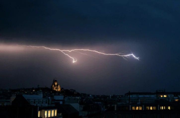 Un éclair dans un ciel d'orage près de la basilique du Sacré Coeur à Montmartre, le 25 juin 2025 à Paris ( AFP / Julie SEBADELHA )