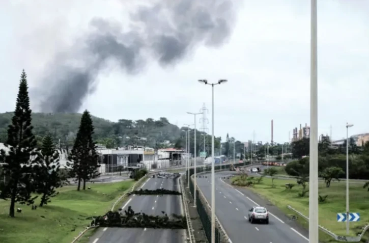 Des fumées à distance avec des barricades sur la route dans le quartier Montravel de Nouméa, le 21 mai 2024 en Nouvelle-Calédonie ( AFP / Theo Rouby )