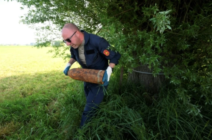 Un membre de l'équipe de déminage de la DOVO ramasse de vieux obus de la Première Guerre mondiale trouvés dans la campagne du nord-ouest de la Belgique, près d'Ypres, le 19 mai 2025 ( AFP / Nicolas TUCAT )