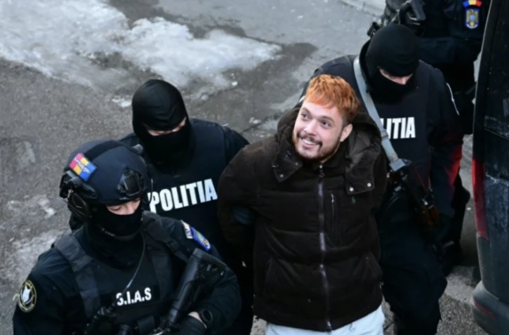 Mohamed Amra escorté par des policiers, le lendemain de son arrestation à Bucarest le 23 février 2025 ( AFP / Daniel MIHAILESCU )