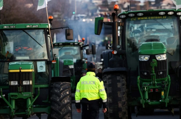 Un policier se tient devant des tracteurs bloquant l'autoroute A6, le 31 janvier 2024 près de Chilly-Mazarin en Essonne