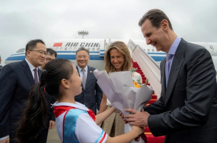 Photo diffusée par l'agence officielle syrienne Sana montrant le président syrien Bachar al-Assad (d) et la Première dame Asma al-Assad (2e d) à leur arrivée à l'aéroport de Pékin, le 21 septembre 2023