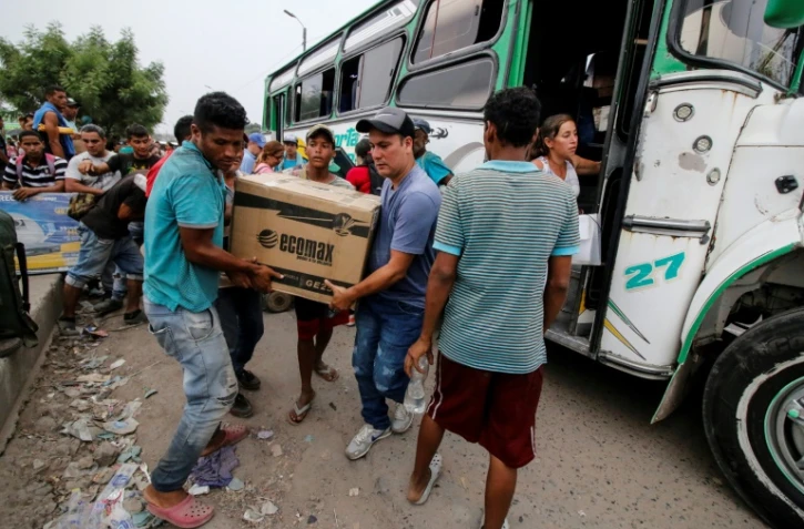 Josué Angulo (c avec la casquette) transporte avec un ami un groupe électrogène qu'il vient d'acheter à Cucuta ville frontière entre la Colombie et le Venezuela, le 10 avril 2019
