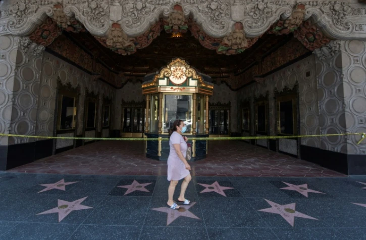 Une femme marche devant le fameux cinéma El Capitan à Hollwood, fermé à cause du coronavirus, à Los Angeles, le 12 juin 2020 