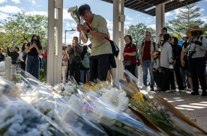 Des personnes se rassemblent le 29 novembre 2025 pour déposer des fleurs devant le complexe résidentiel de Wang Fuk Court à Hong Kong à la suite de l’incendie meurtrier survenu trois jours auparavant