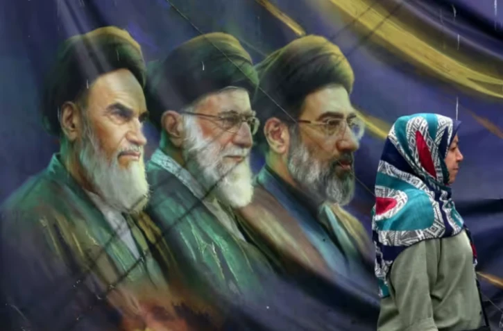 Une Iranienne passe devant les portraits des trois guides suprêmes iraniens depuis l'avènement de la République islamique, le 28 mai 2026 à Téhéran ( AFP / - )