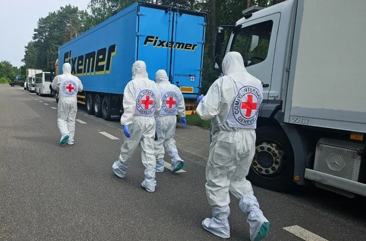 Cette photographie, prise et publiée par le Siège de coordination pour le traitement des prisonniers de guerre le 11 juin 2025, montrerait des représentants de la Croix-Rouge internationale passant devant le cortège de réfrigérateurs du convoi transportant les corps de soldats ukrainiens, au milieu de l'invasion russe en Ukraine. -  Coordinating Headquarters for the Treatment of Prisoners of War / AFP