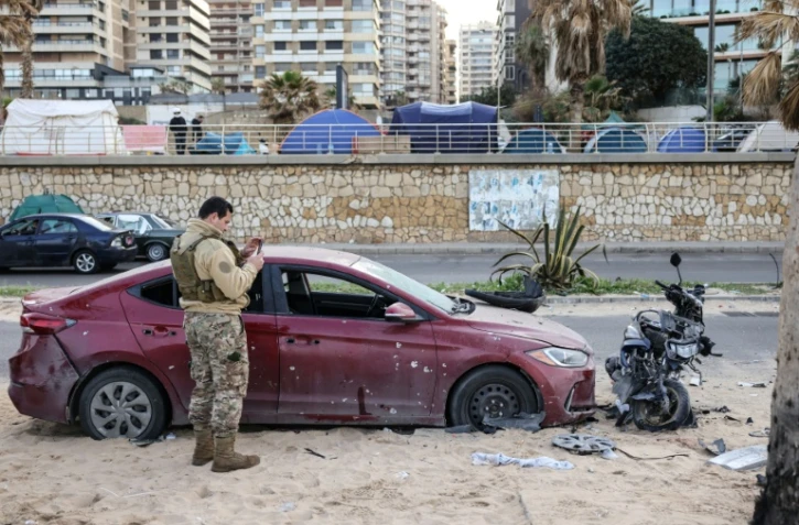 Un soldat inspecte un véhicule endommagé sur le site d'une frappe aérienne israélienne dans la zone côtière de Ramlet al-Bayda à Beyrouth, le 12 mars 2026 au Liban