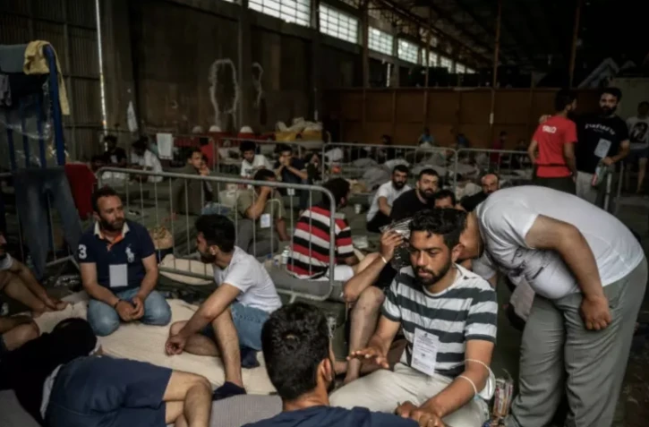 Des migrants, survivants d'un naufrage, installés dans un entrepôt du port de Kalamata, le 15 juin 2023 en Grèce ( AFP / Angelos TZORTZINIS )